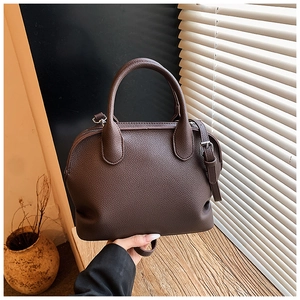 Detailed macro view of dark brown pebble leather texture and sturdy handle on a shell bag
