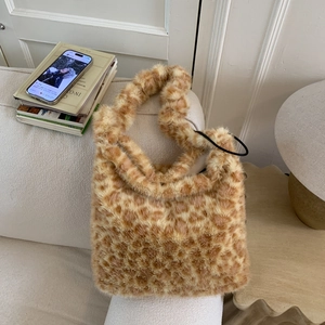 Detail of soft leopard print faux fur shoulder bag with plush wide strap on sofa
