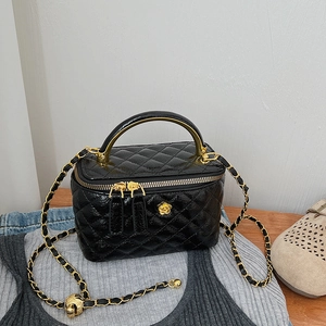 Close-up of a black quilted leather vanity bag with a gold camellia floral ornament