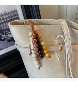 Detailed close-up of ethnic beaded charm hanging on a beige lychee leather tote bag