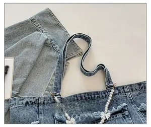 Detail of denim tote bag showing comfortable strap with pearls and bow charms
