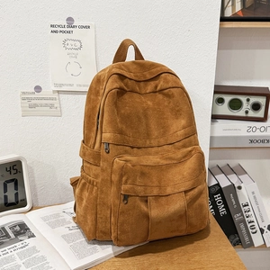 Detail view of brown vintage canvas backpack with multiple pockets on a wooden desk