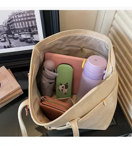 Top-down view of a spacious beige tote bag interior showing a large main compartment and pockets