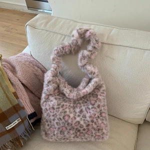 Detail of pink leopard print faux fur tote bag with fluffy texture on sofa