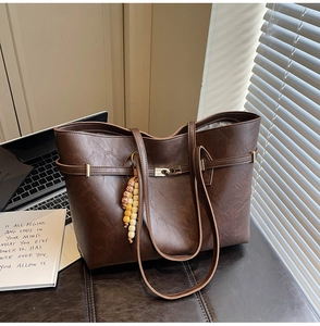 Detail of vintage brown tote bag texture with metal buckle and decorative beaded keychain