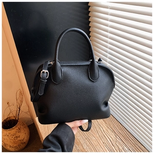 Detail of black lychee grain texture on a shell bag with silver metal buckles and strap