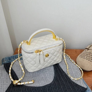 Detailed shot of white quilted leather bag with camellia medal and golden handle