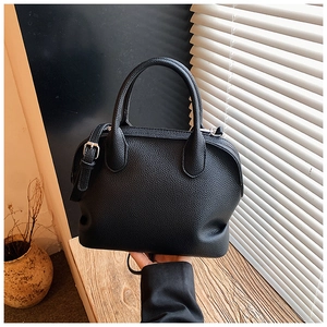Detailed view of black lychee grain leather shell bag with silver metal buckle and strap
