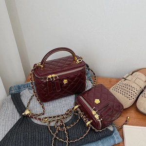 Macro view of burgundy patent leather box bags with quilted pattern and gold flower