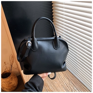Detail showing matte black Boston shell bag with adjustable thin strap and top handles