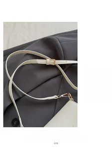 Détail de la bandoulière réglable et boucle en métal doré sur un sac en cuir blanc