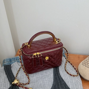 Detail of burgundy quilted patent leather with golden camellia logo and chain strap