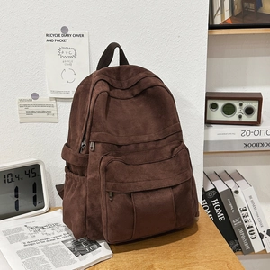 Close-up of vintage brown suede backpack with front zipper pocket on a wooden desk