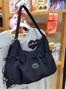 Détail du sac fourre-tout en nylon noir avec plis à cordon et écusson de mode