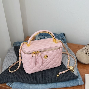 Macro detail of pink quilted leather bag with golden camellia motif and metal handle