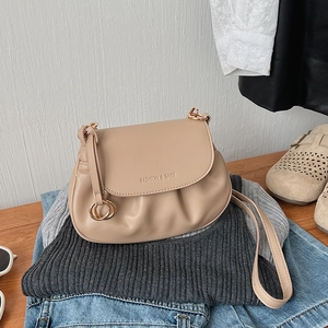 Close-up of beige pleated crossbody bag with FASHION & BAGS logo on garment