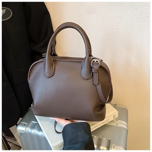 Detailed close-up of dark brown lychee leather handbag with silver hardware and dual handles