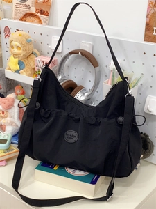 Détail du sac hobo noir avec poche à cordon plissée et patch logo circulaire