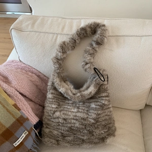 Close-up of leopard print plush tote bag showing soft faux fur texture on a sofa