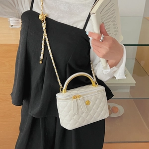 Detail of white quilted crossbody bag with golden camellia logo and chain handle