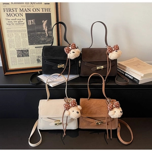 Detail of four matte Kelly bags in black, brown, and cream with plush bear charms