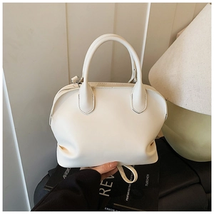 Close-up of cream shell handbag with adjustable strap and textured leather finish