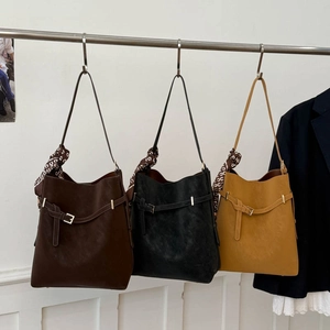 Three leather bucket bags in dark brown, black, and yellow with decorative silk scarves