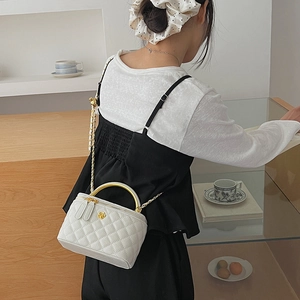 Close-up of quilted white leather bag with golden camellia buckle and round metal handle