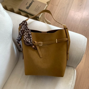 Detail of mustard yellow bucket bag with vintage scarf on a minimalist sofa