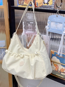 Détail du sac fourre-tout en nylon blanc cassé avec cordons latéraux sur une étagère