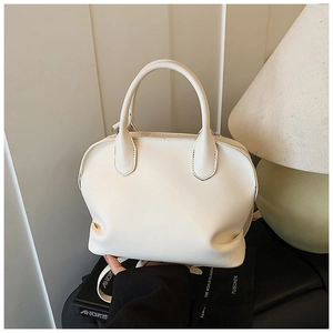 Detailed close-up of cream PU leather shell bag with cylindrical handles and smooth texture