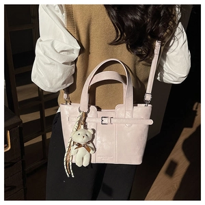 Detailansicht der rosa Eimertasche mit Lederschnalle, Bärenanhänger und Metallteilen