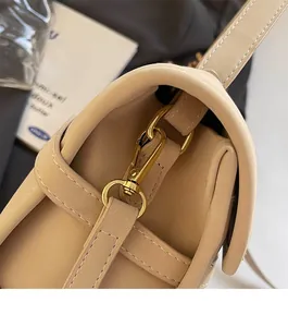 Detail of durable gold lobster clasp and white stitching on khaki leather handbag strap