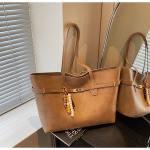 Macro detail of camel brown tote bag with leather straps and colorful bead tassel