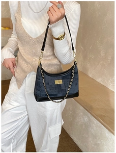 Detail of denim patchwork dumpling bag with gold chain strap and metal turn-lock closure