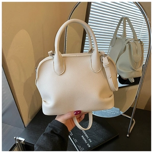 Close-up of beige shell bag featuring lychee texture leather and round handles