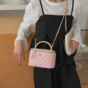 Detail of pink quilted crossbody bag with golden camellia and chain strap on model
