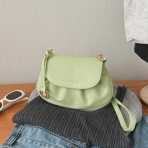 Detail of light green pleated crossbody bag with gold hardware and logo on soft fabric