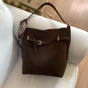 Retro dark brown suede bucket bag with a decorative silk scarf on a white sofa