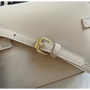Detail of adjustable beige leather shoulder strap with golden metal buckle and fine stitching