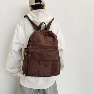 Brown corduroy backpack shown on model featuring large front pocket and vintage style