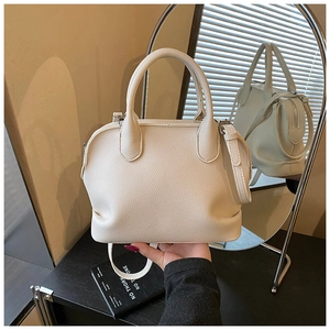 Close-up of cream lychee texture shell bag with round handles and metal zipper details