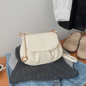 Detailed view of cream pleated crossbody bag with gold hardware and logo engraving