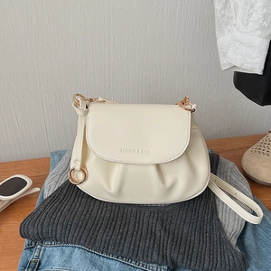 Detail of cream pleated square bag on denim jeans with golden hardware and fashion logo