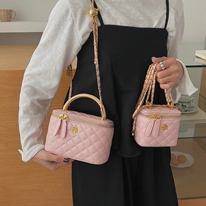 Detail of pink quilted chain bag with golden camellia logo and metal top handle