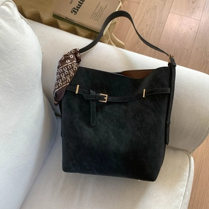 Detail of black vintage bucket bag with decorative scarf on a white sofa setting