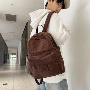 Detailed view of deep brown faux suede backpack with multi-pocket design on model