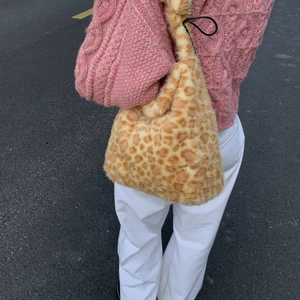 Detailed view of leopard print faux fur tote bag with black drawstring and lock