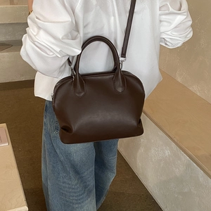 Detail view of a dark brown Boston bag featuring polished leather and metal zipper