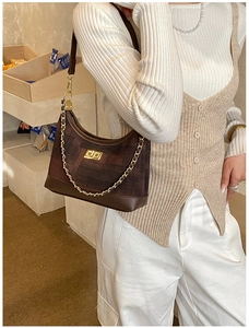 Detailed view of brown fabric underarm bag featuring gold chain and turn-lock closure
